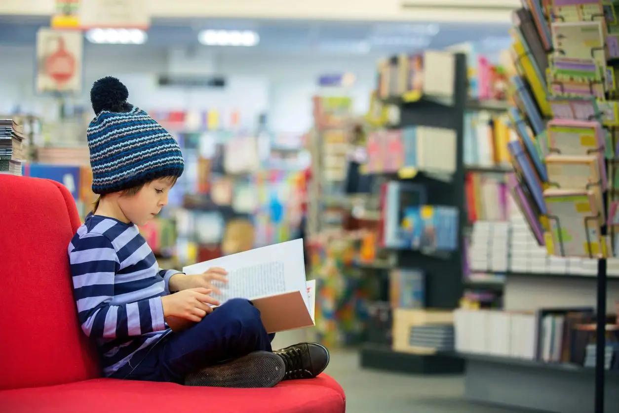 A child sitting on the floor reading a book.