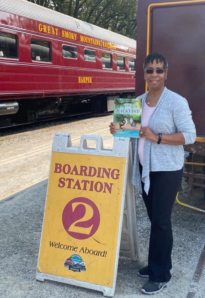 A woman standing in front of a train with a sign for boarding station 2.