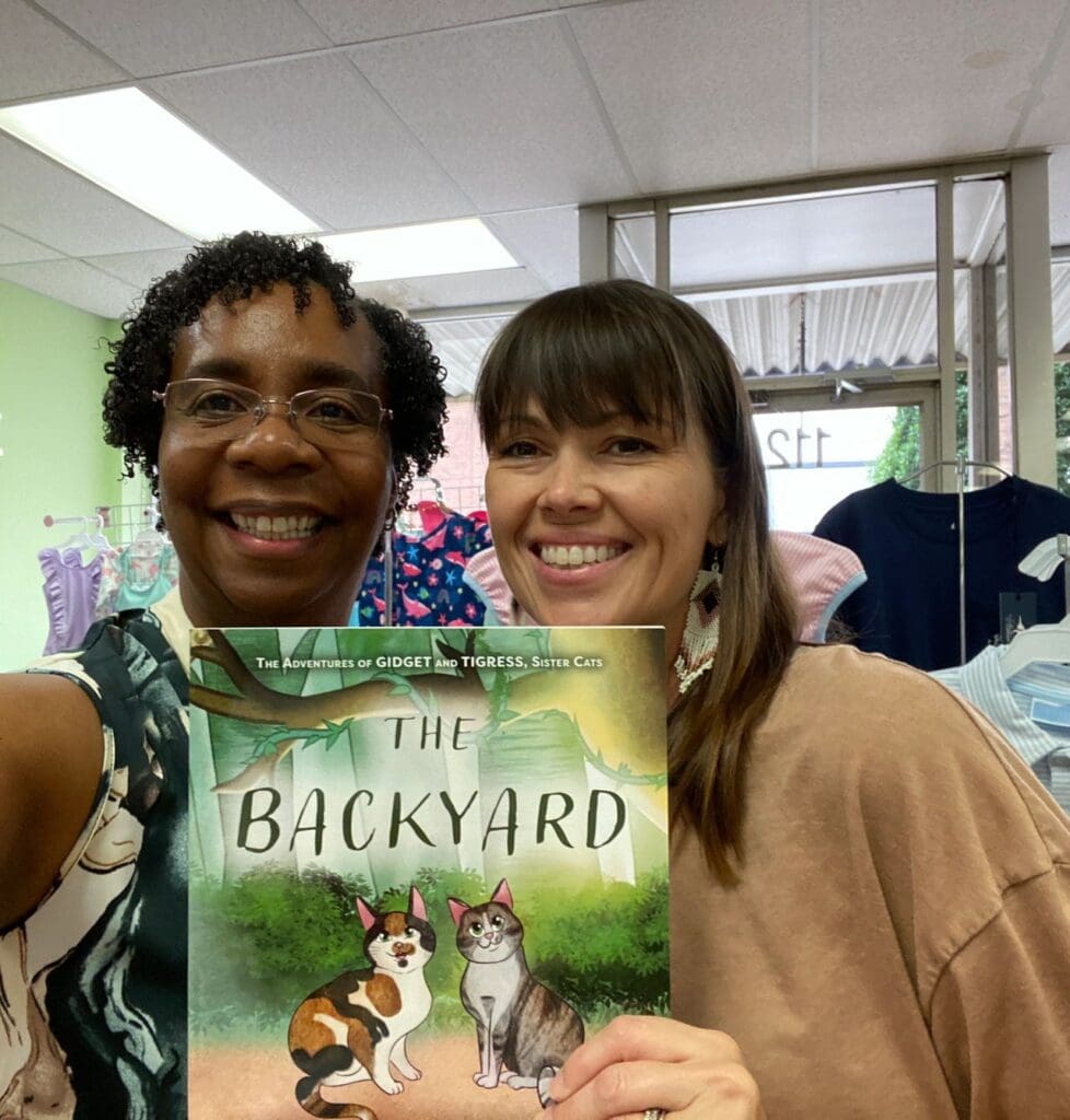 Two women holding up a book in a store.