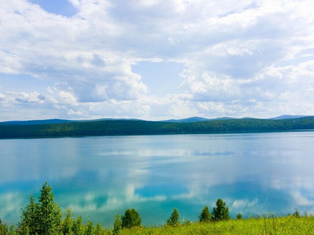 A body of water with trees and mountains in the background.