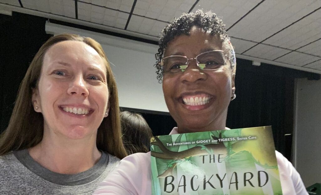 Two women smiling with a book in their hands.