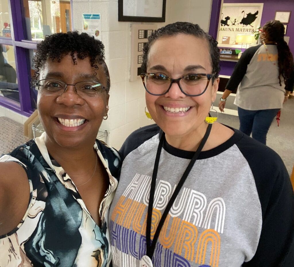 Two women standing next to each other in a hallway.