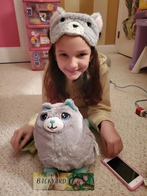 A girl sitting on the floor next to a stuffed animal.