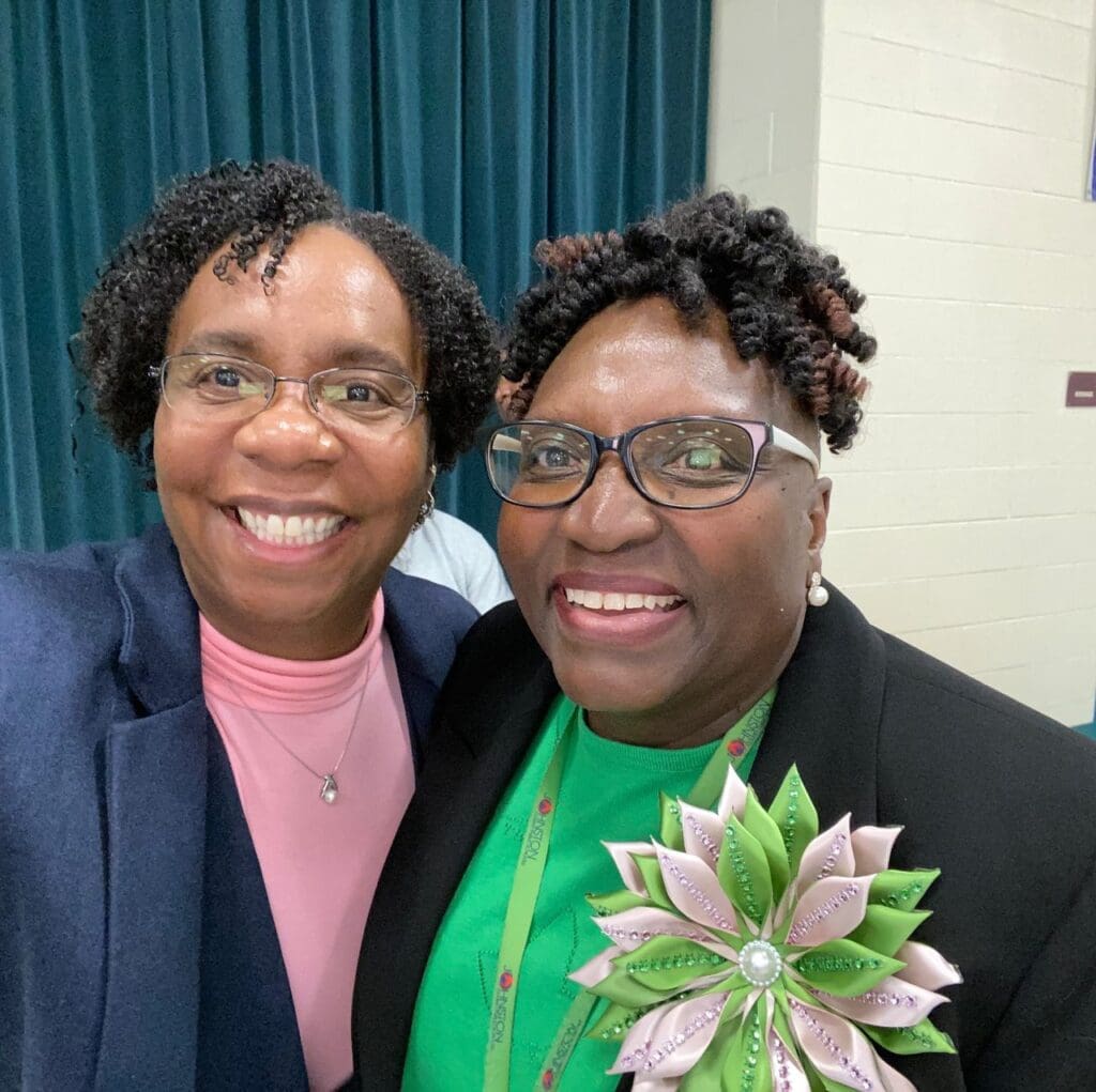 Two women smiling for the camera at a conference.