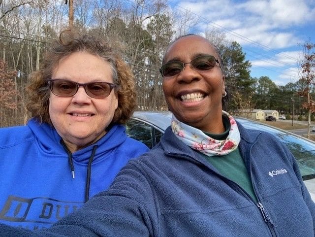 Two women taking a selfie in front of a car.