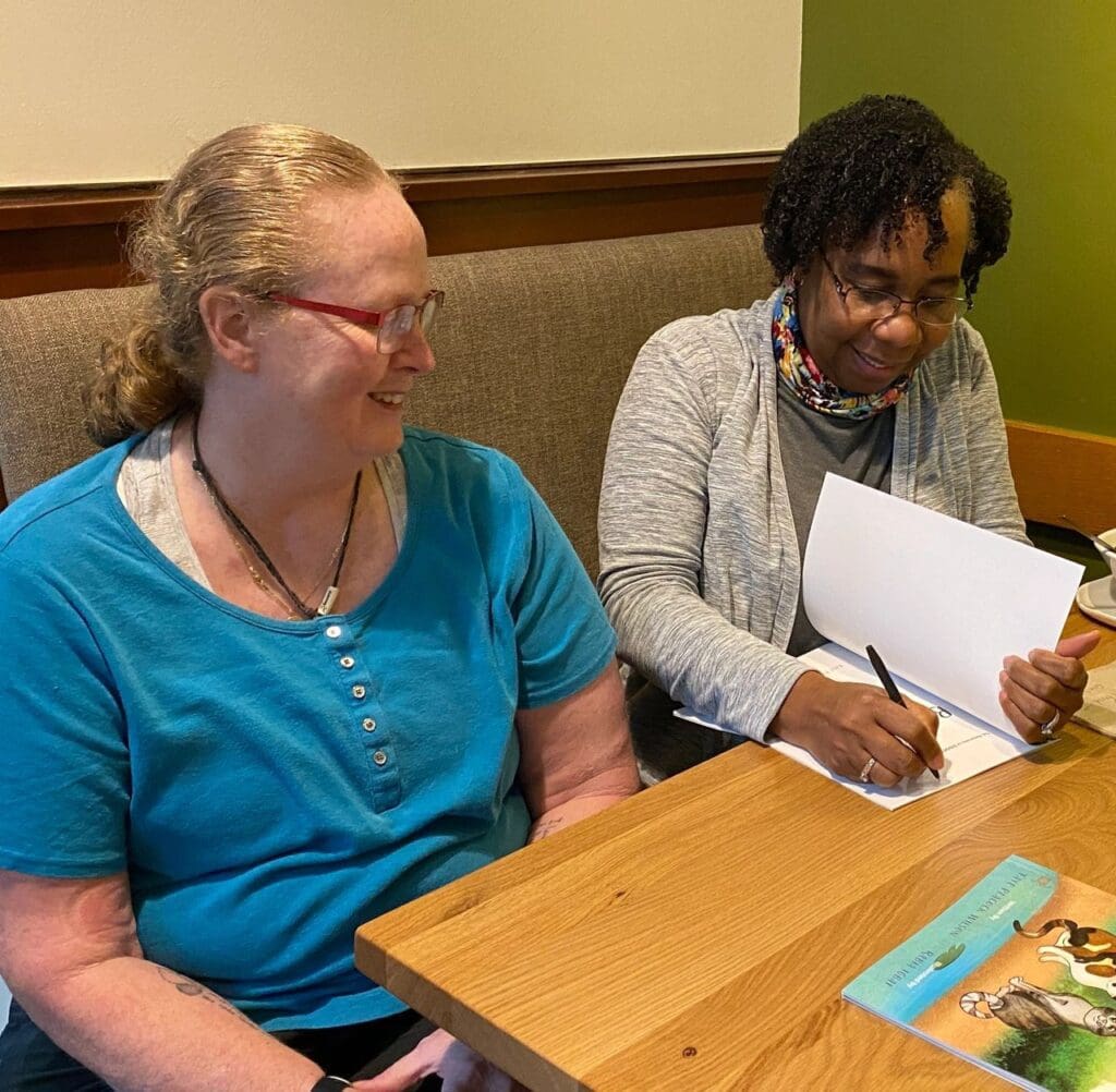 Two women signing books at a table.