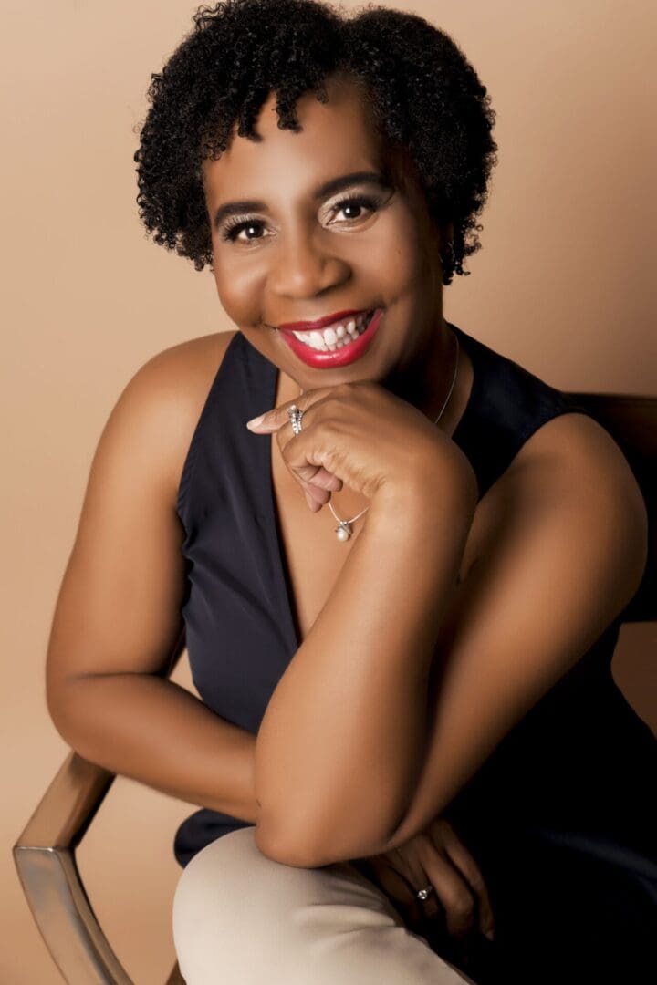 A black woman sitting in a chair with a smile on her face.