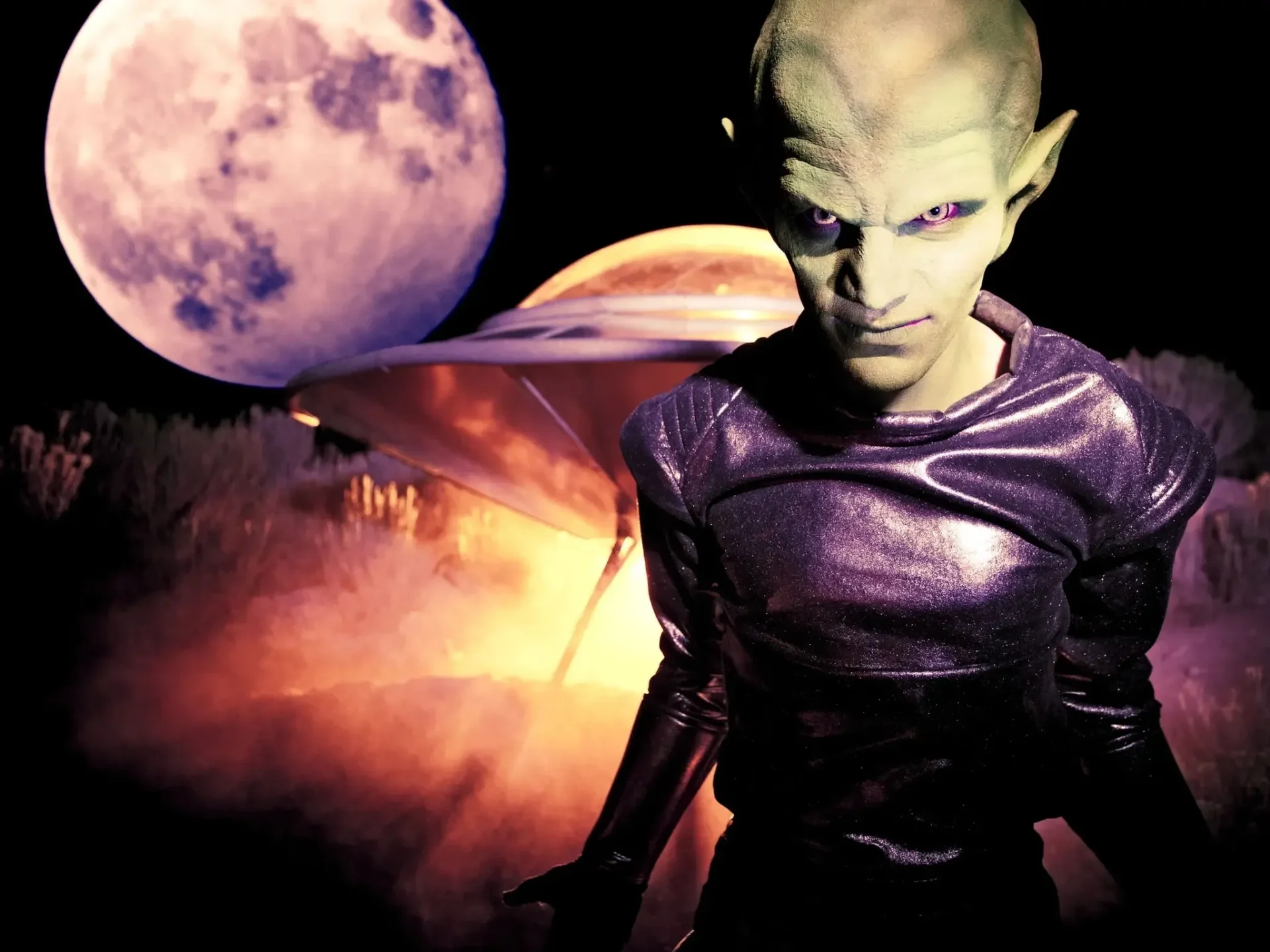 Alien with UFO and moonlit background.