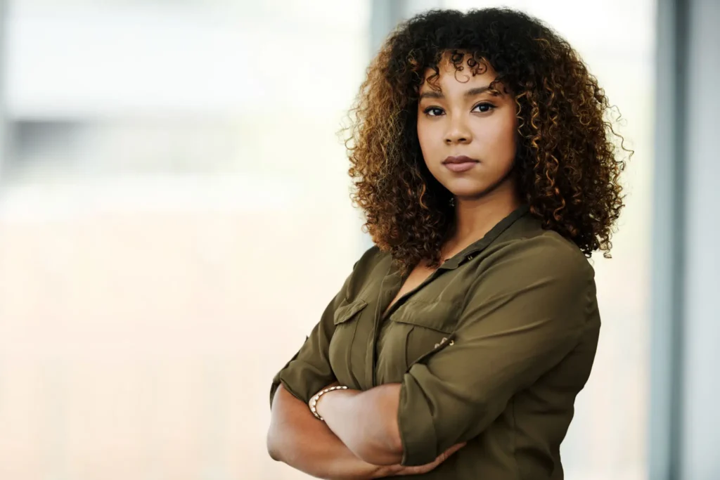 Confident woman with curly hair, arms crossed