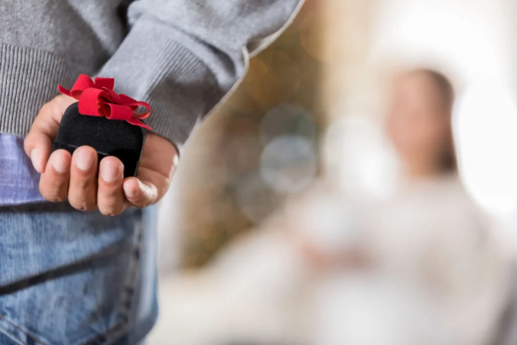 Person hiding a small gift behind their back.