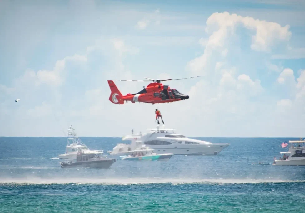 Helicopter rescue over yachts in ocean.