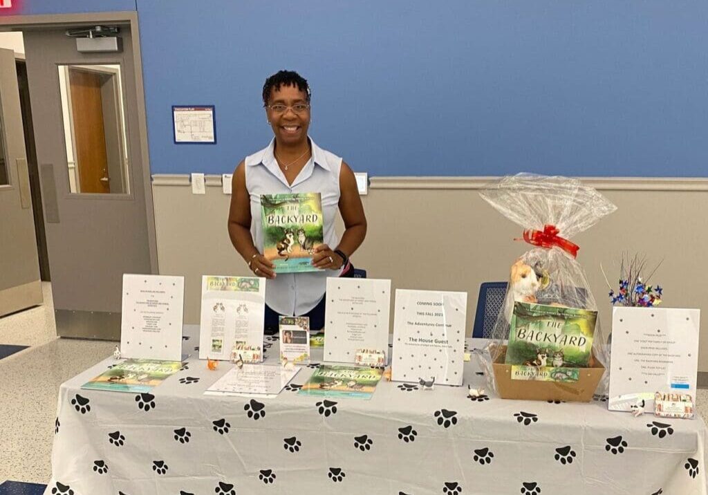 A woman standing next to a table with a book.