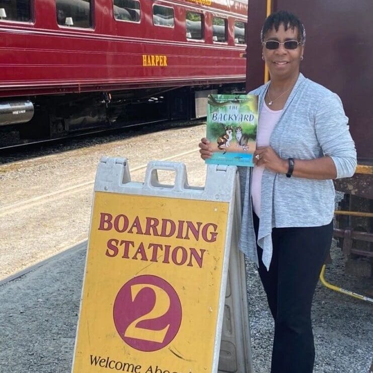 A woman standing in front of a train with a sign for boarding station 2.