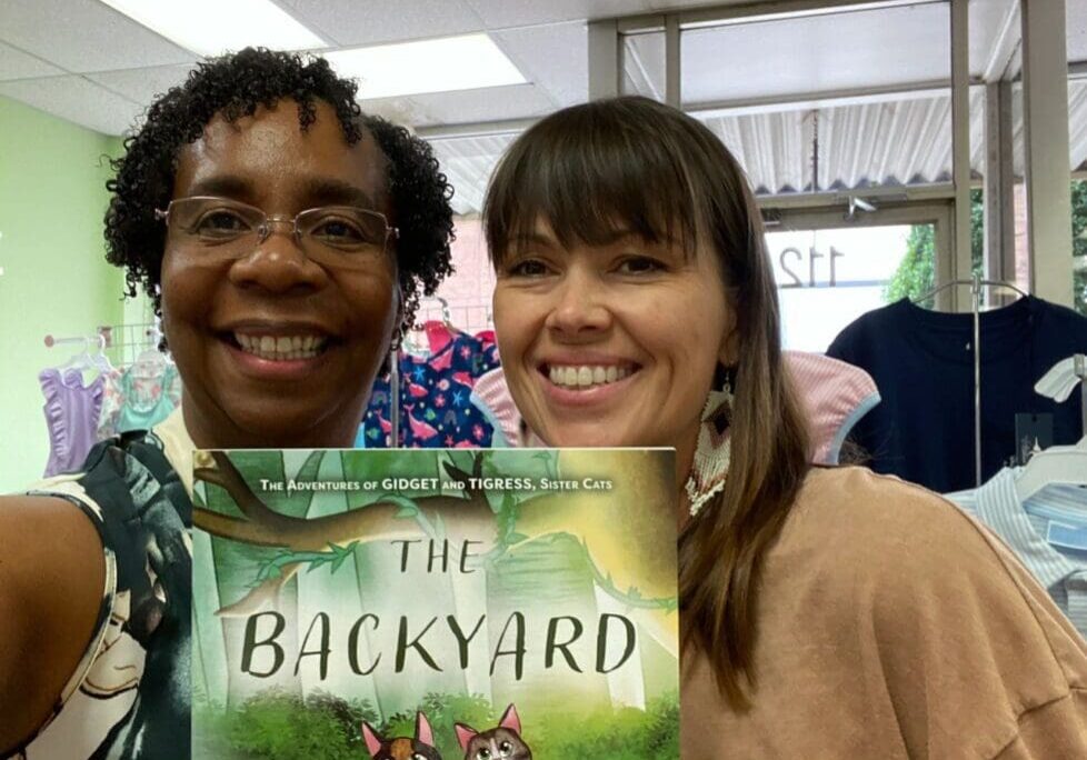 Two women holding up a book in a store.