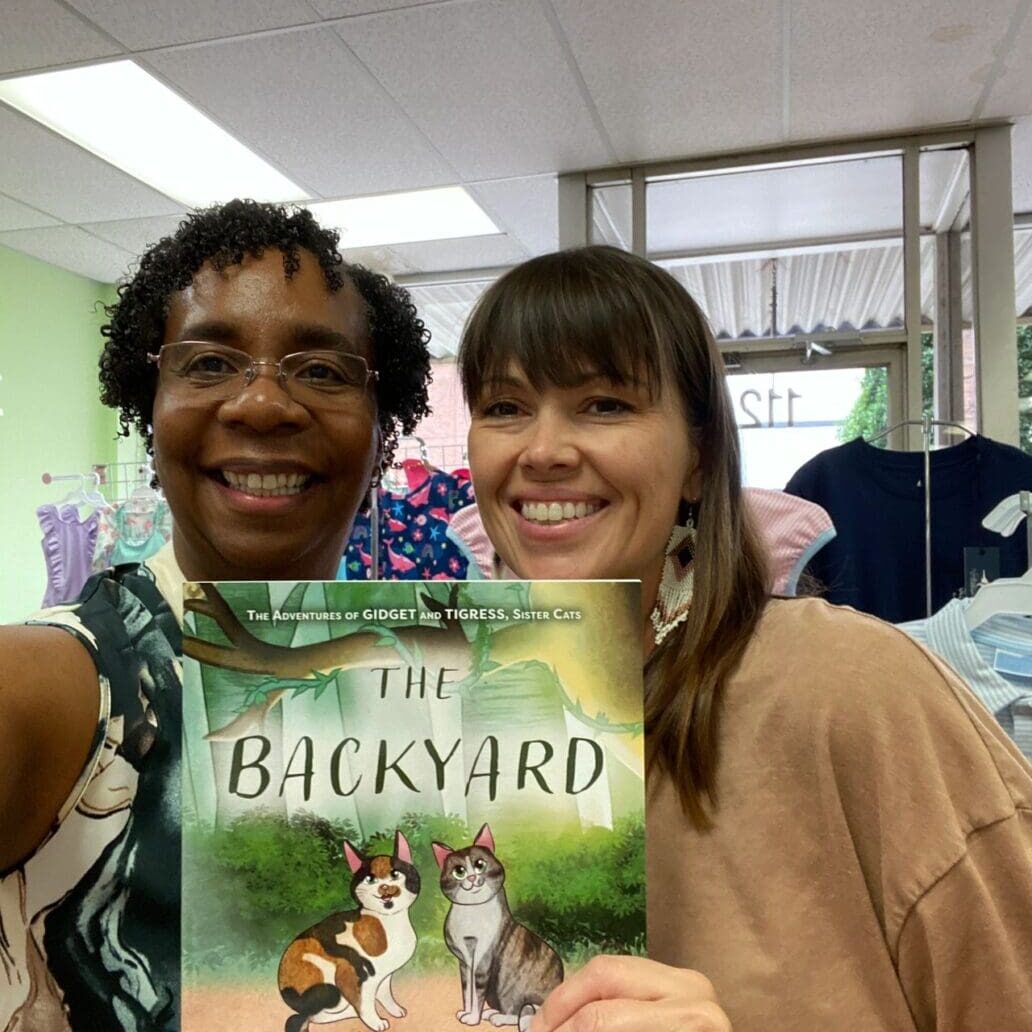 Two women holding up a book in a store.