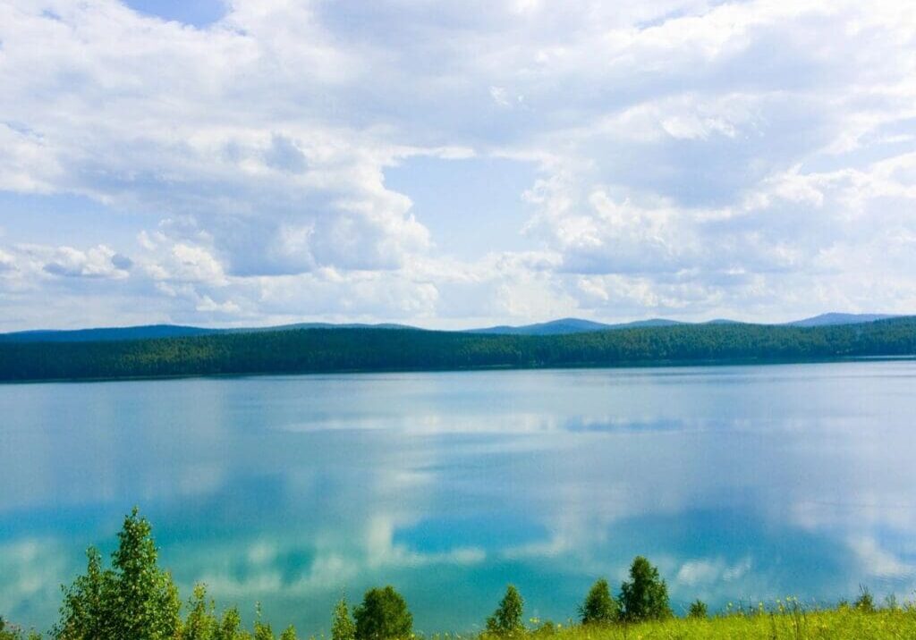 A body of water with trees and mountains in the background.