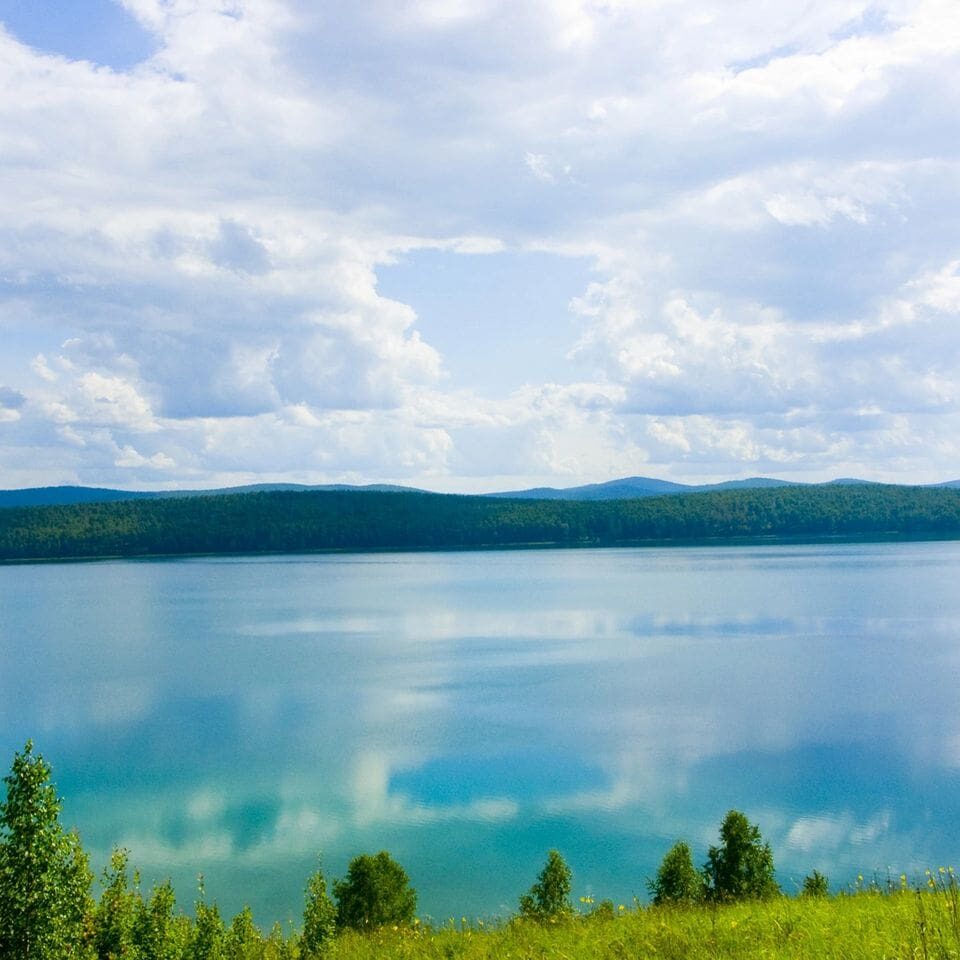 A body of water with trees and mountains in the background.