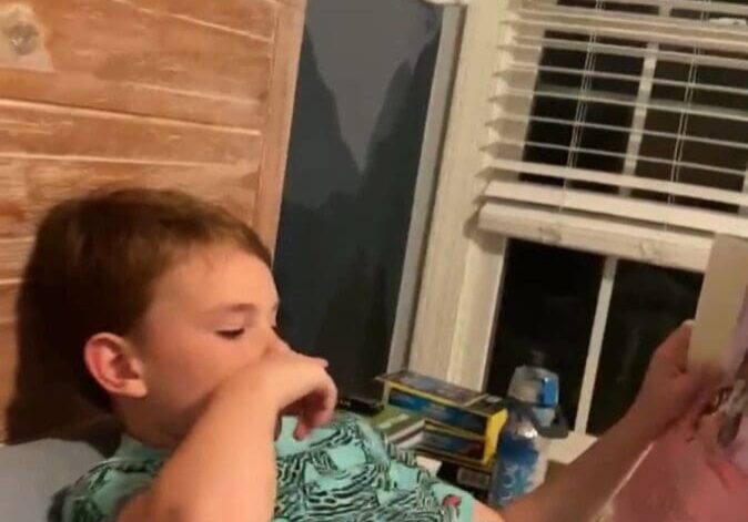 A boy laying in bed reading a book.