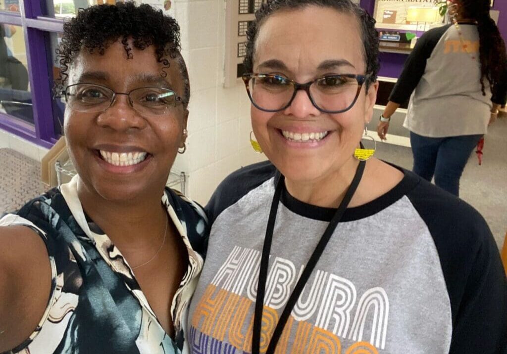 Two women standing next to each other in a hallway.