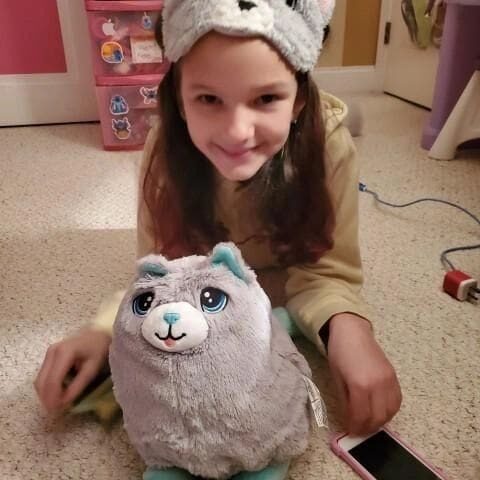 A girl sitting on the floor next to a stuffed animal.