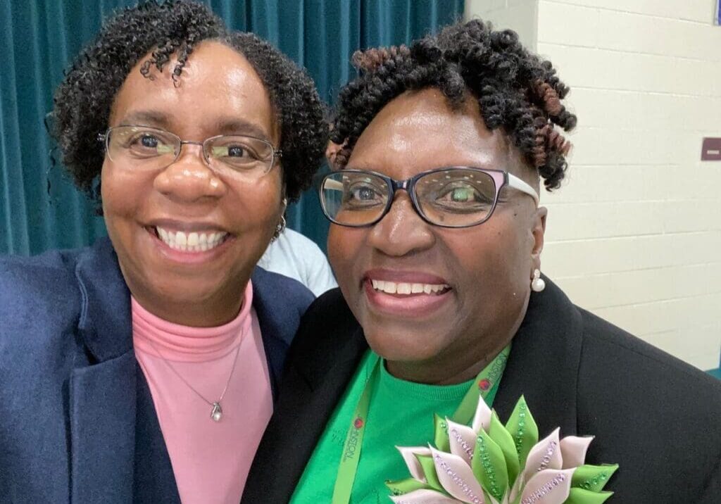 Two women smiling for the camera at a conference.