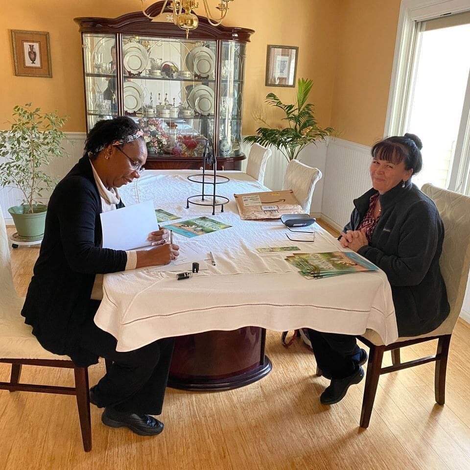 Two women sitting at a table in a living room.