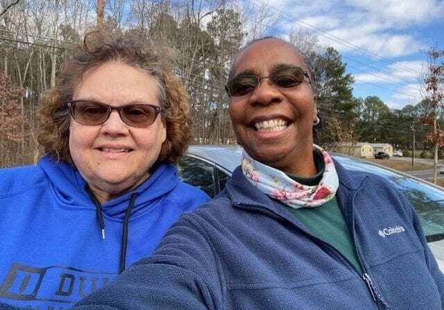 Two women taking a selfie in front of a car.