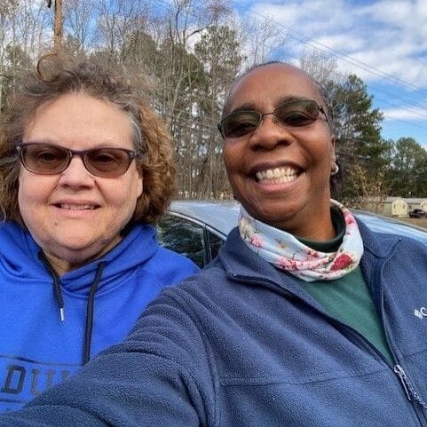 Two women taking a selfie in front of a car.