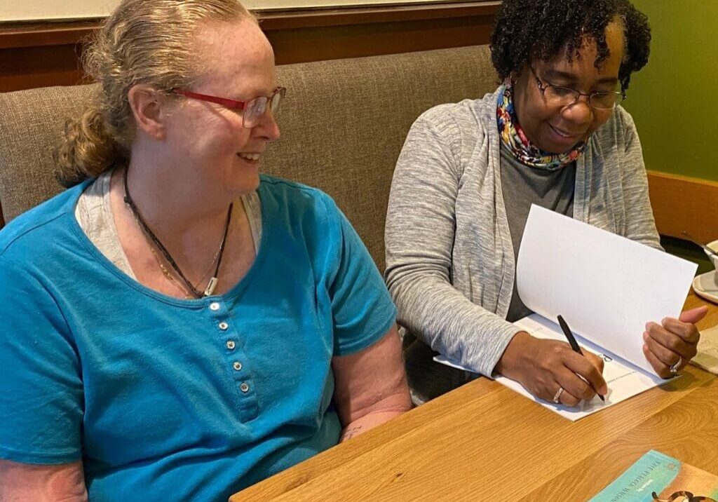 Two women signing books at a table.