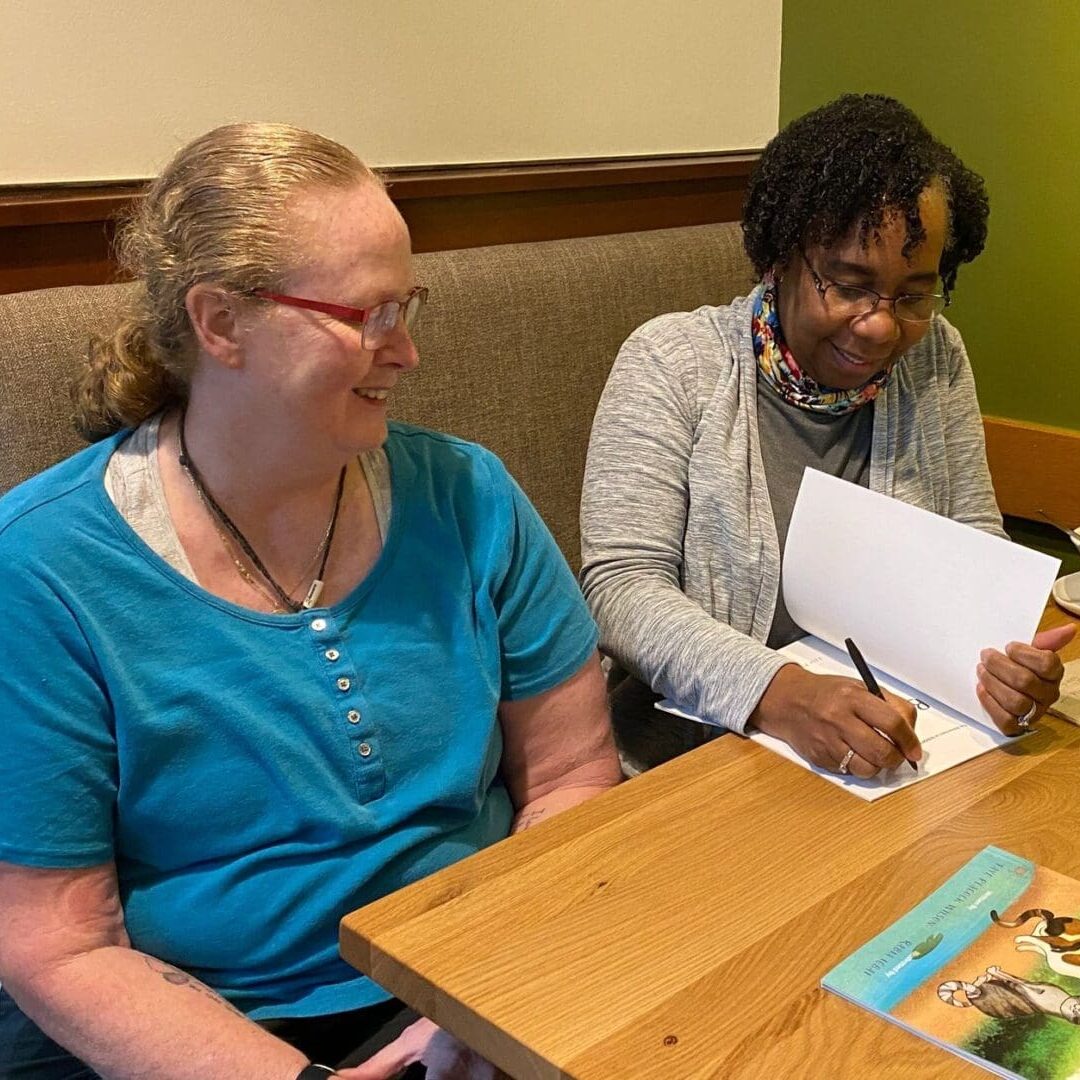 Two women signing books at a table.